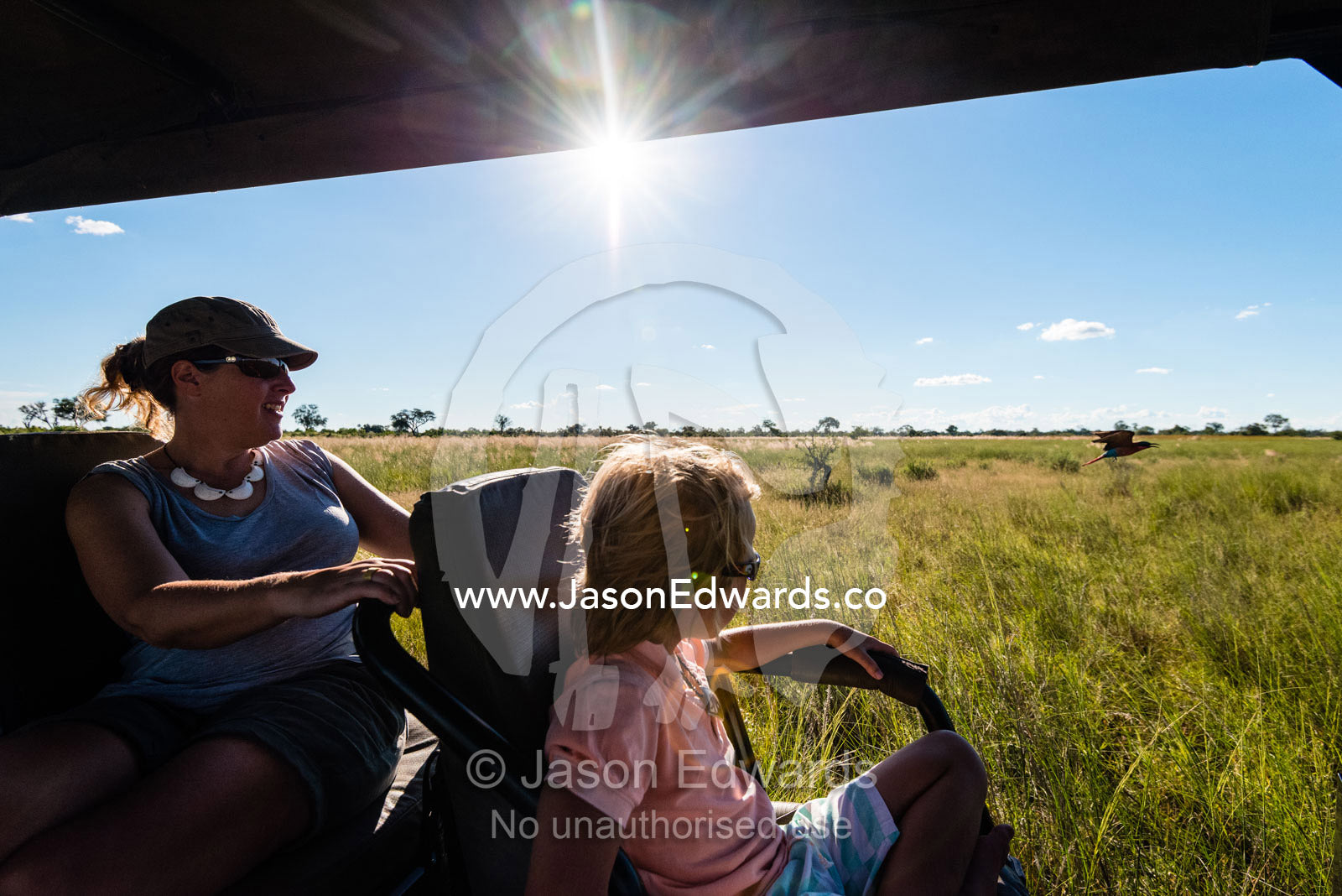 A mother and son in a safari 4wd searching for wildlife. Selinda Reserve, Linyanti Region, Northern Botswana.
