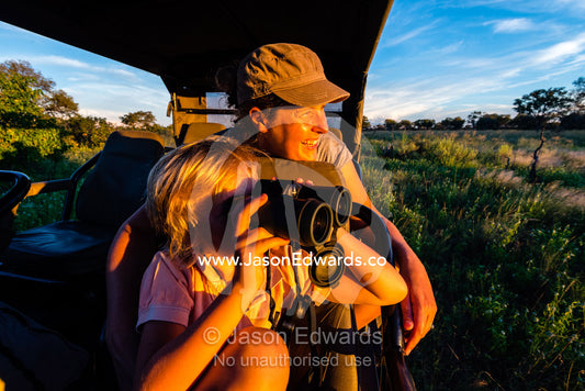 A mother and son in a safari 4wd watching wildlife. Selinda Reserve, Linyanti Region, Northern Botswana.