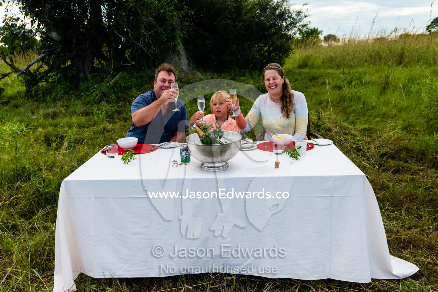 A family celebrates an anniversary breakfast served on a remote floodplain whilst on safari. Selinda Camp, Selinda Reserve, Linyanti Region, Northern Botswana.