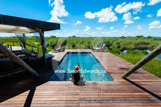 A boy playing in a swimming pool in a luxury safari camp. Selinda Camp, Selinda Reserve, Linyanti Region, Northern Botswana.