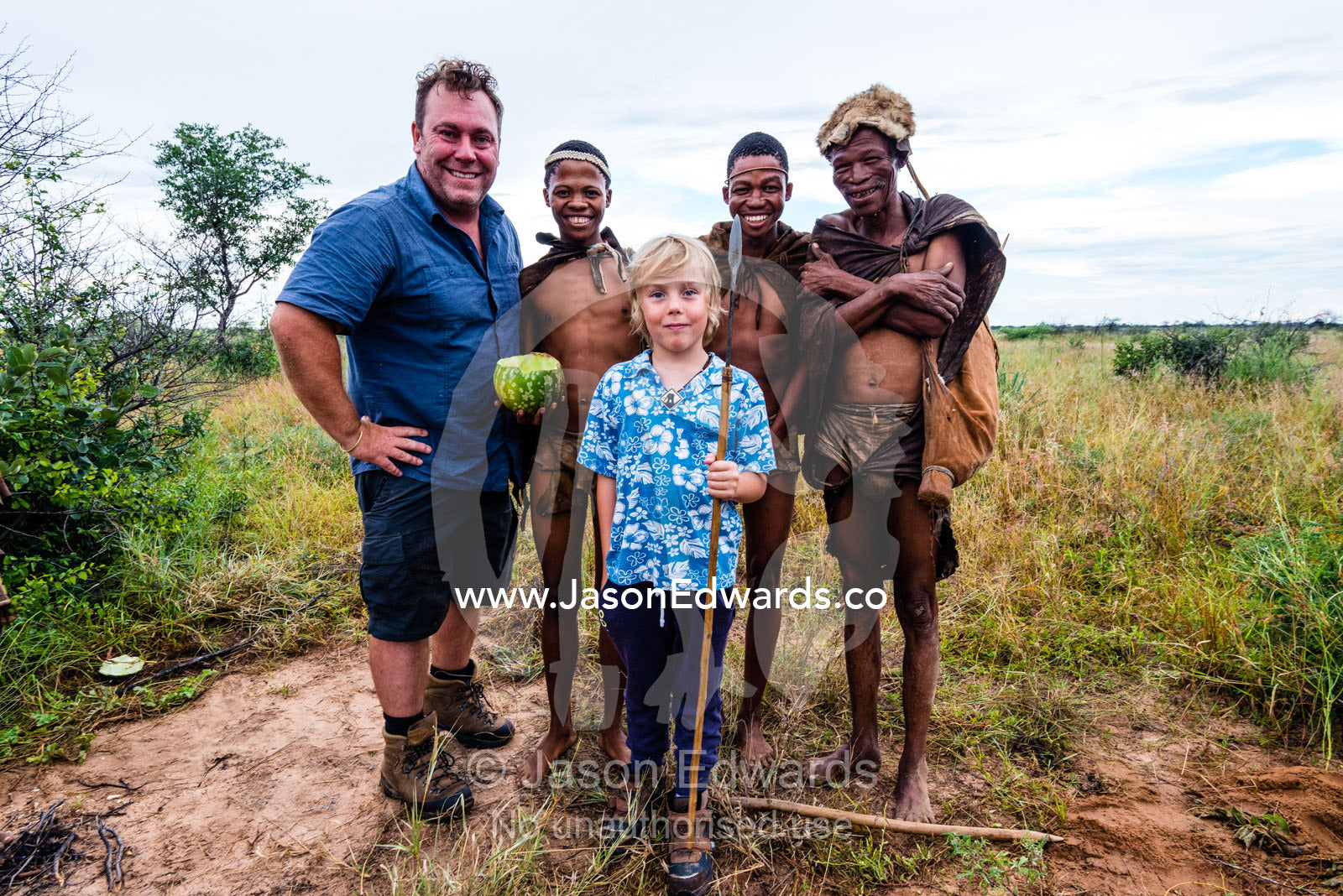 A western father and son with the men of a San Bushmen family in the Kalahari. Kalahari Desert, Botswana.