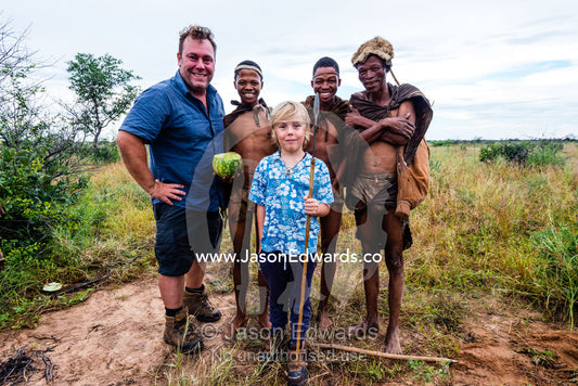 A western father and son with the men of a San Bushmen family in the Kalahari. Kalahari Desert, Botswana.