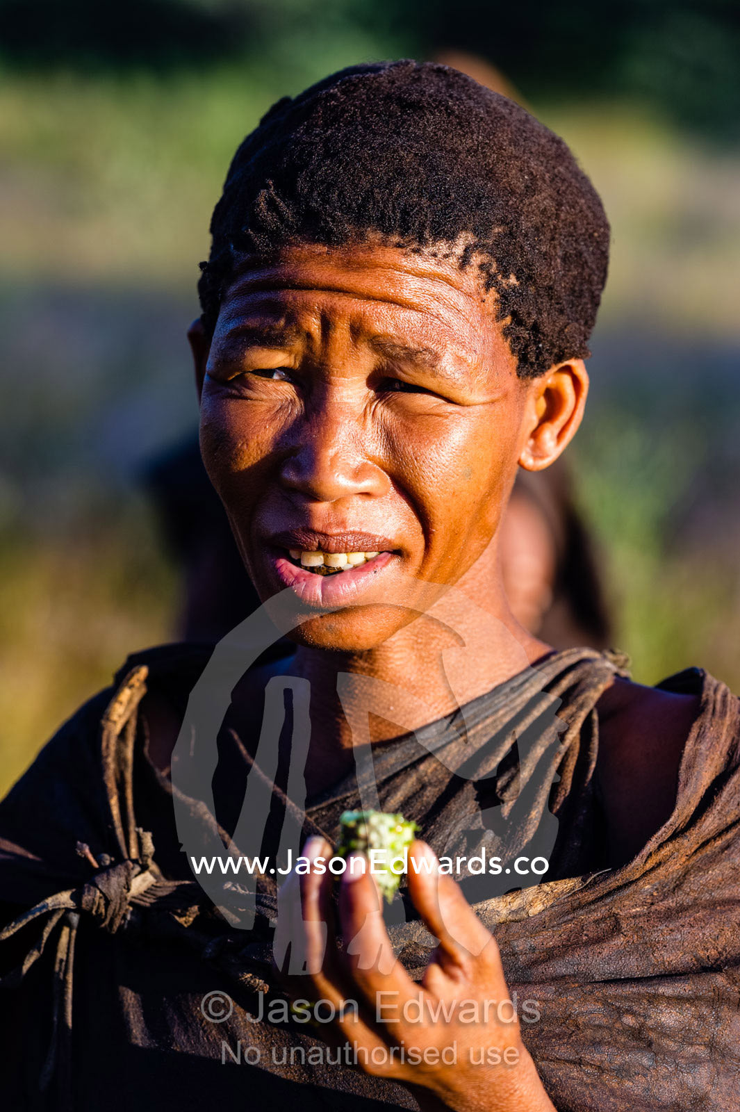 A San Bushmen woman holding food she found in the desert. Kalahari Desert, Botswana.