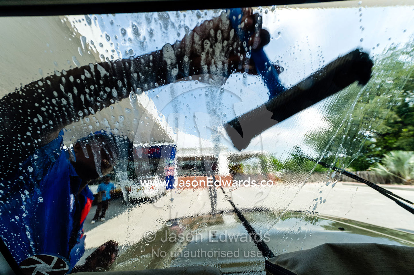 Cleaning mud and dead insects from a 4wd windscreen in a petrol station. Makgadikgadi Pans, Botswana.