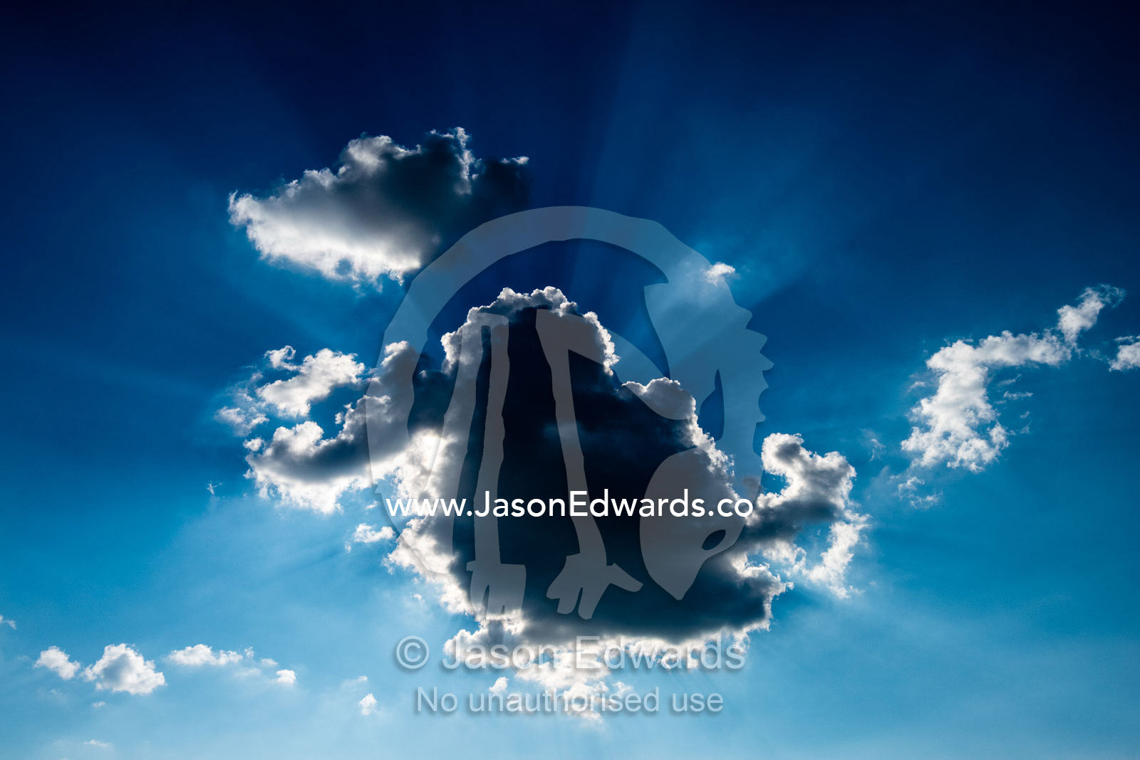 God rays pass from behind clouds in a clear blue sky. Chobe River, Chobe National Park, Botswana.