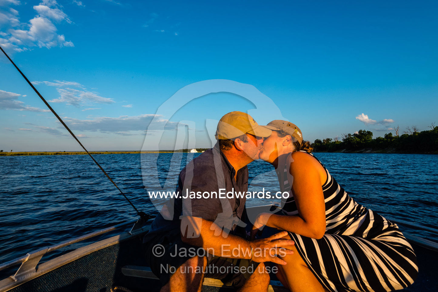 A husband and wife kissing on an African safari boat. Chobe River, Chobe National Park, Botswana.