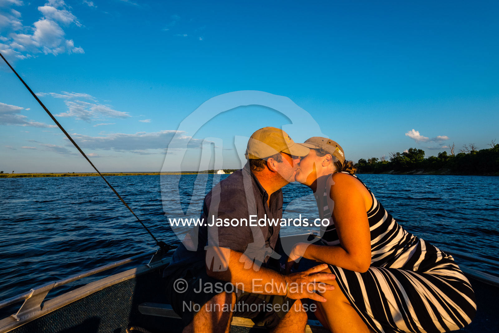 A husband and wife kissing on an African safari boat. Chobe River, Chobe National Park, Botswana.