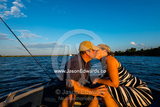 A husband and wife kissing on an African safari boat. Chobe River, Chobe National Park, Botswana.