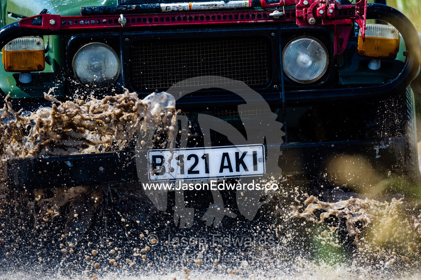 A safari 4wd splashes through the mud of a waterhole. Zarafa Camp, Zibadianja Lagoon, Savute Channel, Linyanti, Botswana.