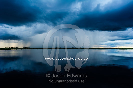 A torrential downpour from a rainstorm over a flooded wetland. Zarafa Camp, Zibadianja Lagoon, Savute Channel, Linyanti, Botswana.