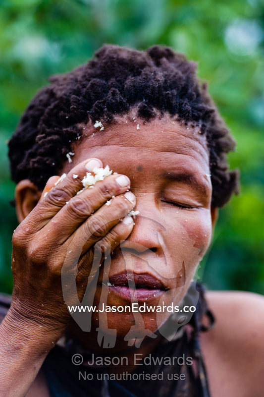 A San Bushmen woman using the pulp from a tuber root to make soap for washing her hands and face. Kalahari Desert, Botswana.