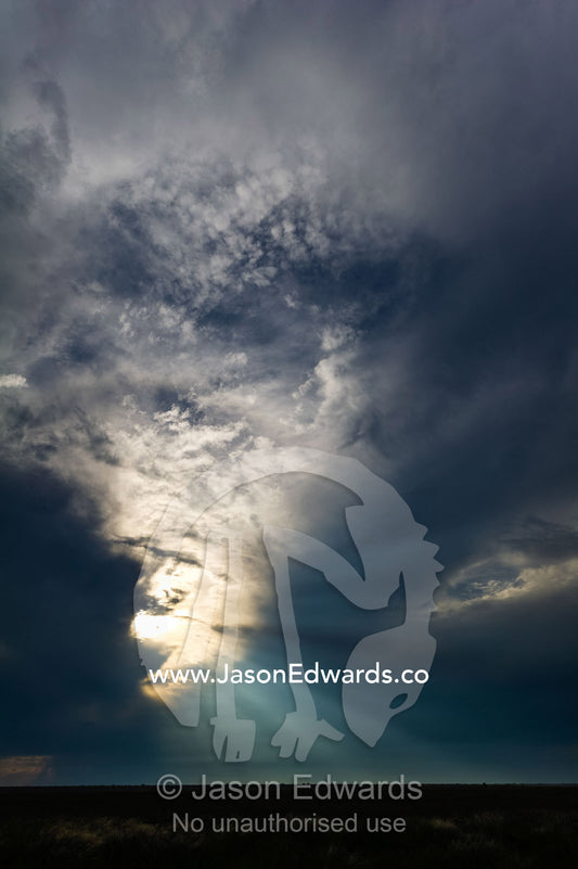 God rays pass through clouds above a flat and featureless plain. Makgadikgadi Pans, Botswana.