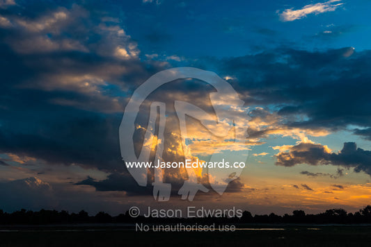 A pastel coloured thunderhead forms over a floodplain at sunset. Chobe National Park, Botswana.