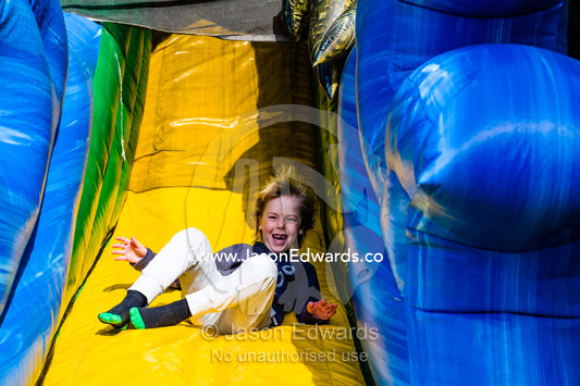 A boy slips down an inflatable slide at an agricultural show. Royal Melbourne Show, Flemington, Melbourne, Victoria, Australia.