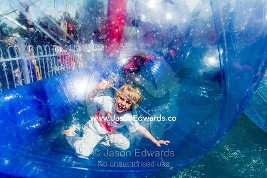 A boy rolls around in an inflatable transparent ball in a swimming pool at an agricultural show. Royal Melbourne Show, Flemington, Melbourne, Victoria, Australia.