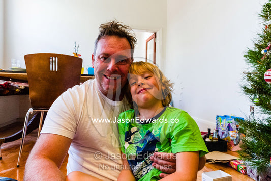 A father and son cuddle on Christmas morning. Carlton North, Melbourne, Victoria, Australia.