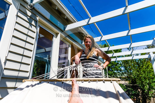 A wife watches her husband resting in a hammock in the sunshine on Christmas day. Malvern East, Melbourne, Victoria, Australia.