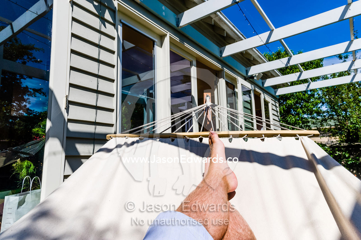 A man rests in the in the sunshine in a hammock on Christmas day. Malvern East, Melbourne, Victoria, Australia.