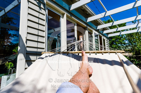 A man rests in the in the sunshine in a hammock on Christmas day. Malvern East, Melbourne, Victoria, Australia.