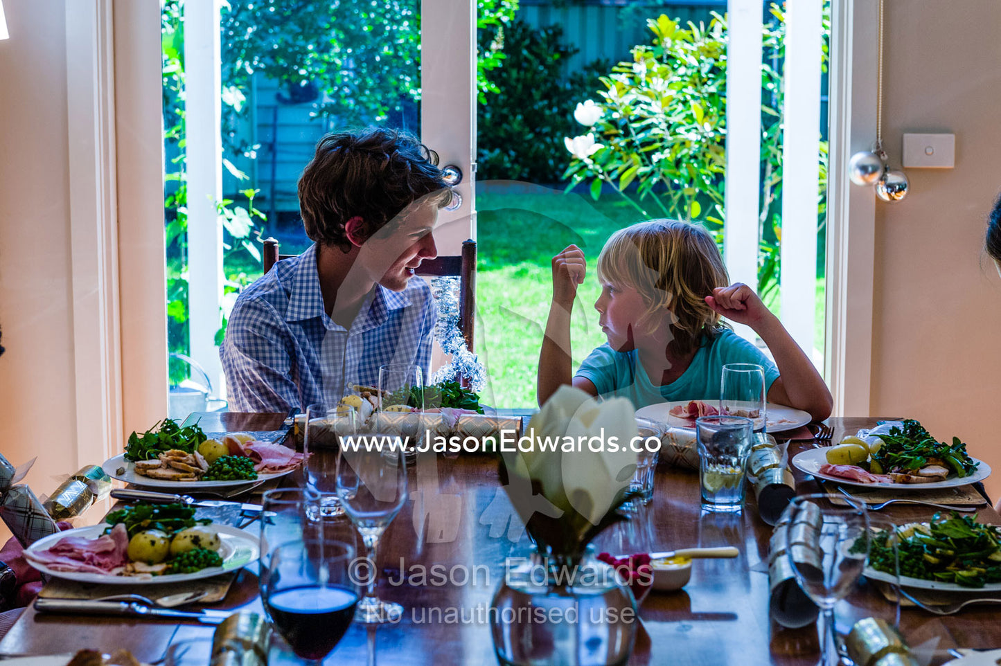 Two cousins wait at a dining table for lunch on Christmas day. Malvern East, Melbourne, Victoria, Australia.