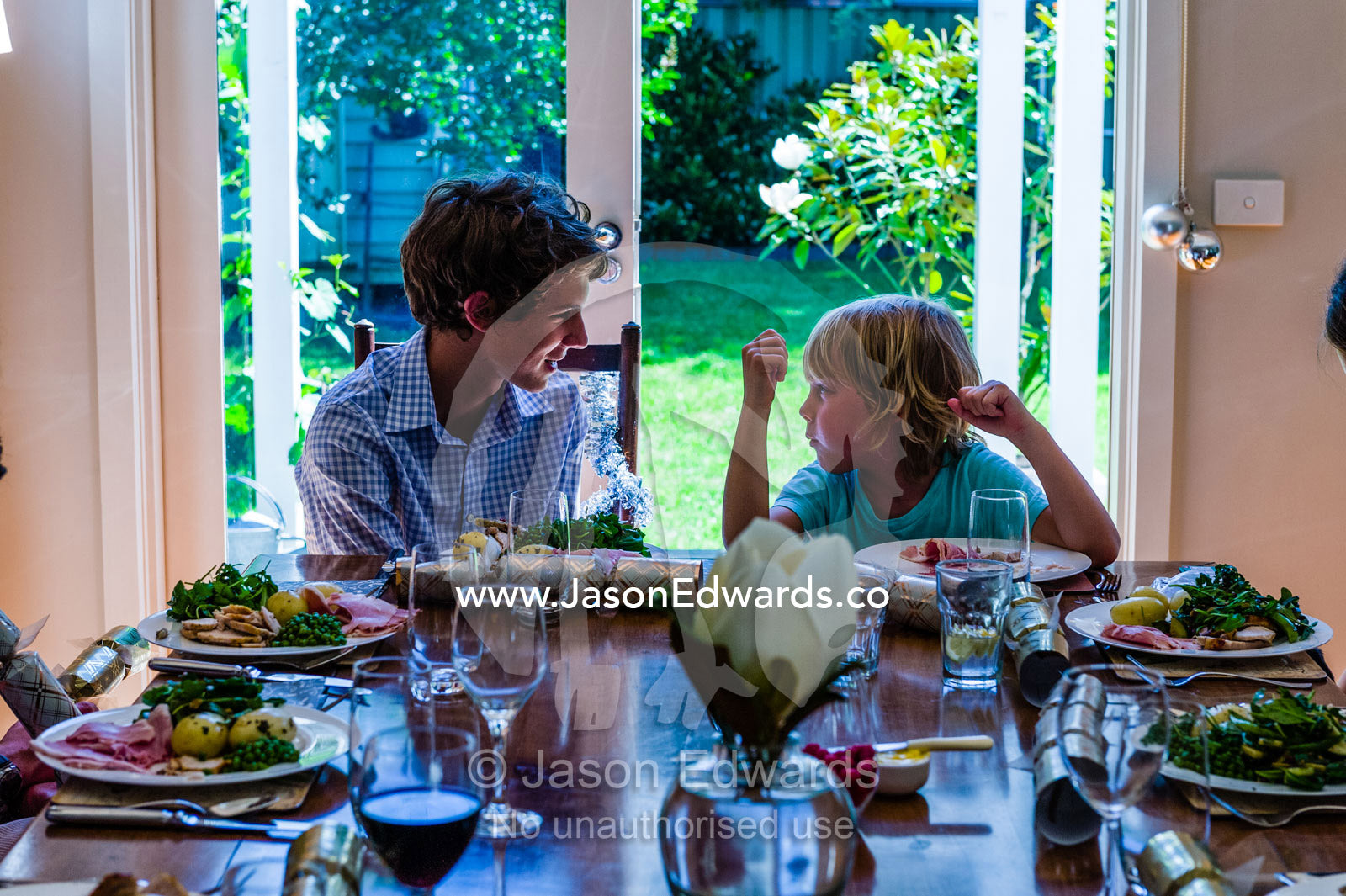 Two cousins wait at a dining table for lunch on Christmas day. Malvern East, Melbourne, Victoria, Australia.