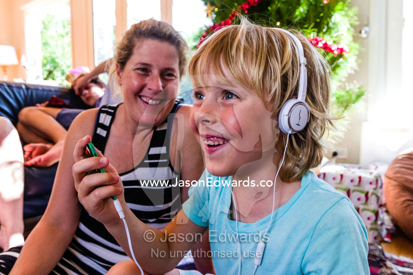 A boy smiles whilst listening to music through headphones for the first time. Malvern East, Melbourne, Victoria, Australia.