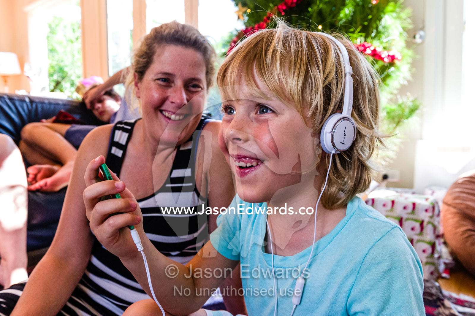 A boy smiles whilst listening to music through headphones for the first time. Malvern East, Melbourne, Victoria, Australia.