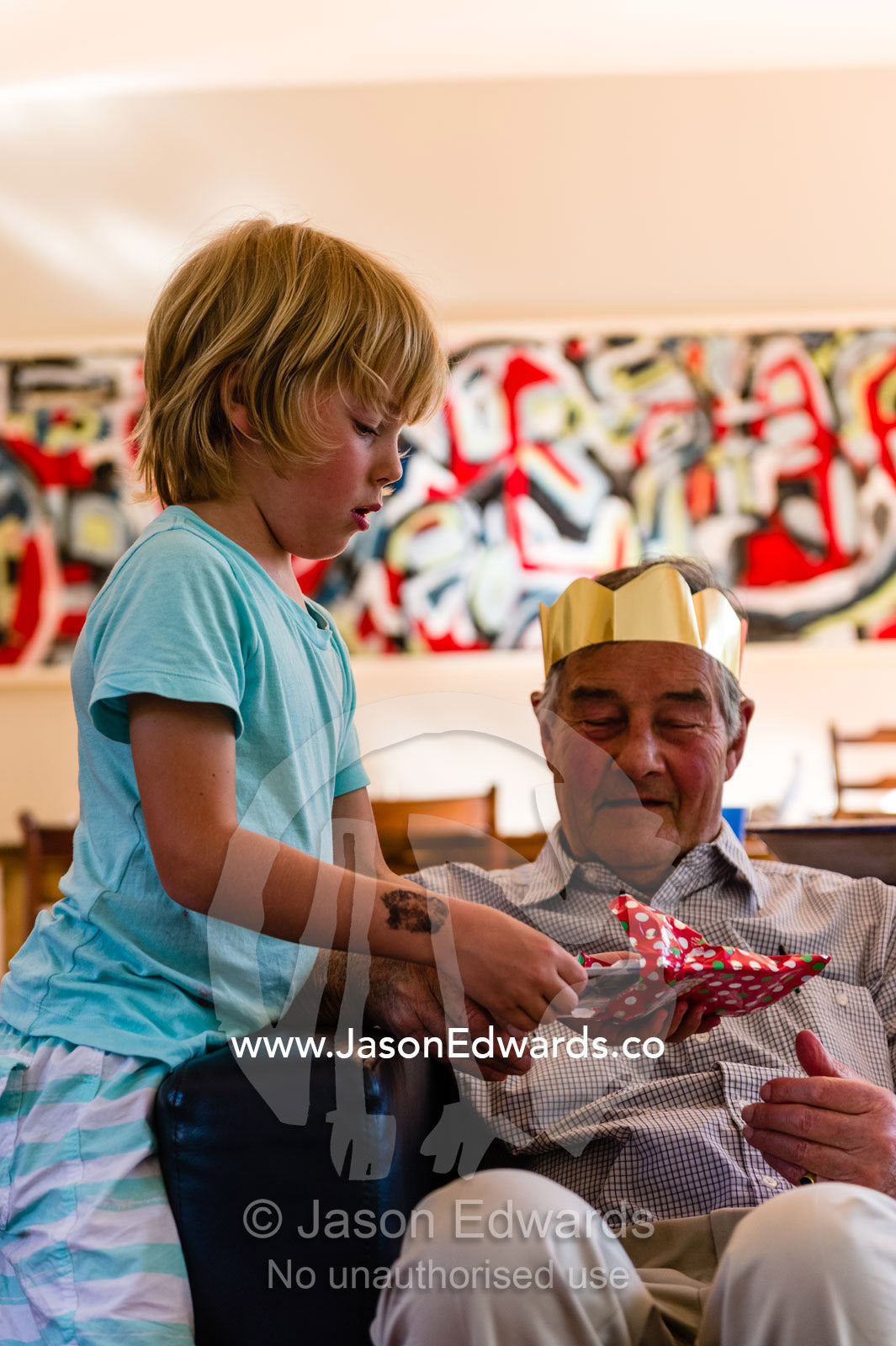 A grandson gives his grandfather a gift on Christmas day. Malvern East, Melbourne, Victoria, Australia.