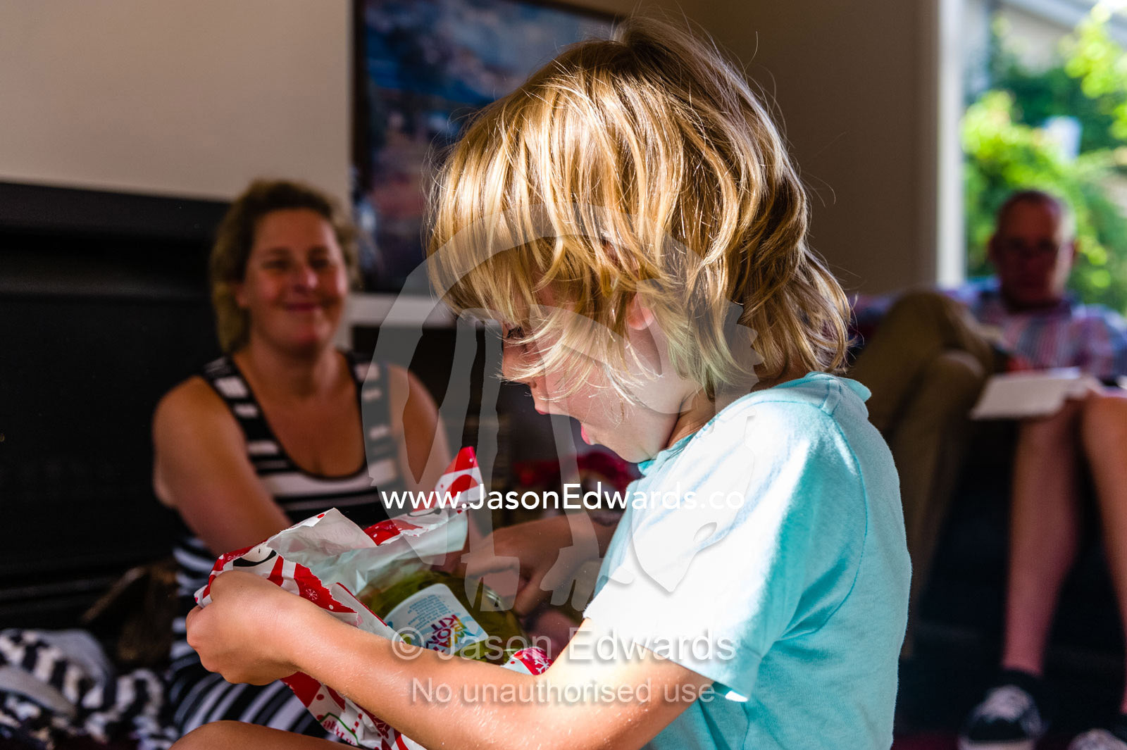 A boy unwraps a Christmas gift of water balloons. Malvern East, Melbourne, Victoria, Australia.