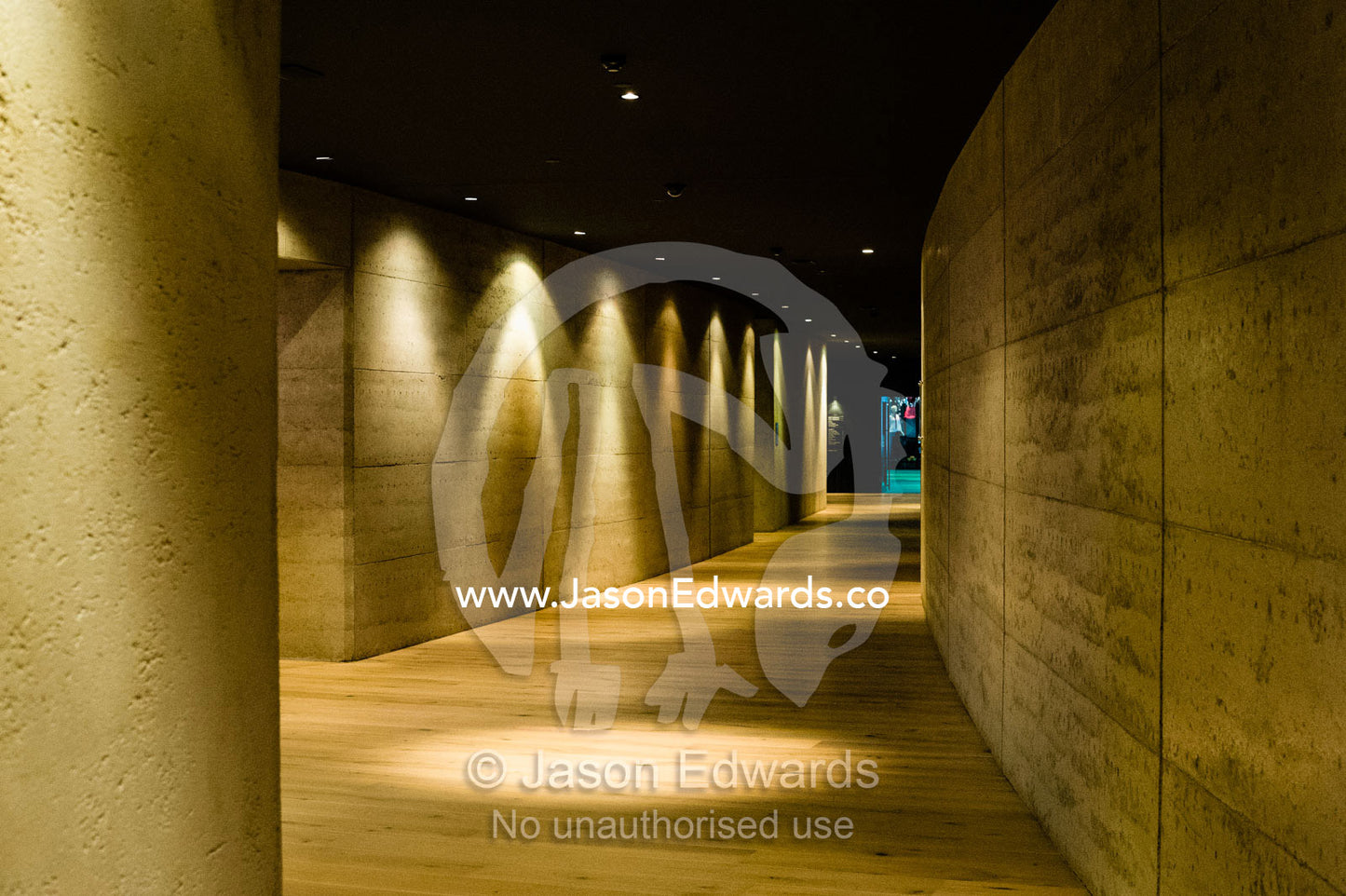 The concrete walls and down lights in a curved hotel corridor. Torquay, Surf Coast, Victoria, Australia.
