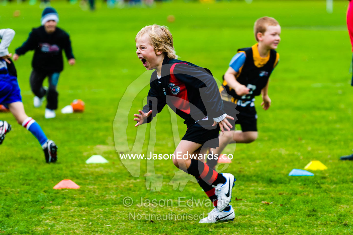 A boy learning to play Australian rules football on a sports field. Edinburgh Gardens, North Fitzroy, Melbourne, Victoria, Australia.