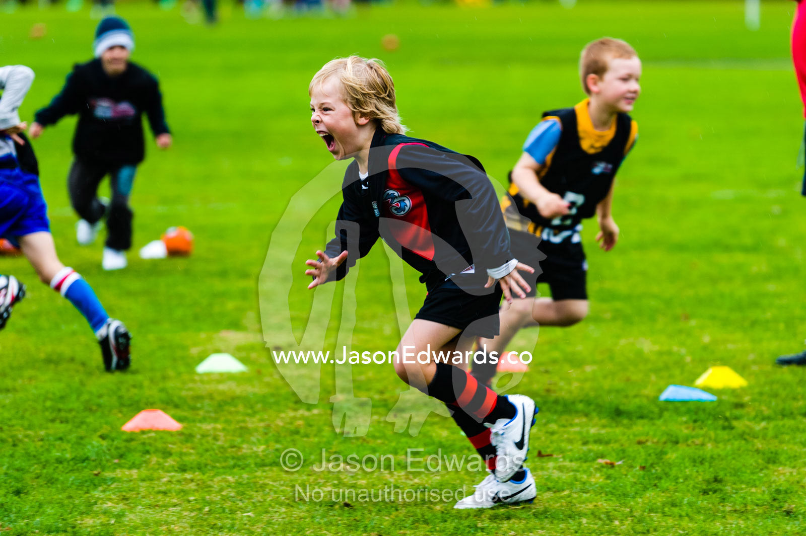 A boy learning to play Australian rules football on a sports field. Edinburgh Gardens, North Fitzroy, Melbourne, Victoria, Australia.