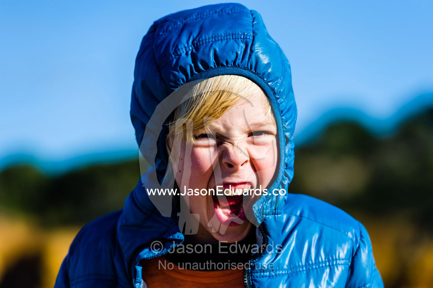 A boy charges at the camera in a game of wrestling and chase on the beach. Torquay, Surf Coast, Victoria, Australia.