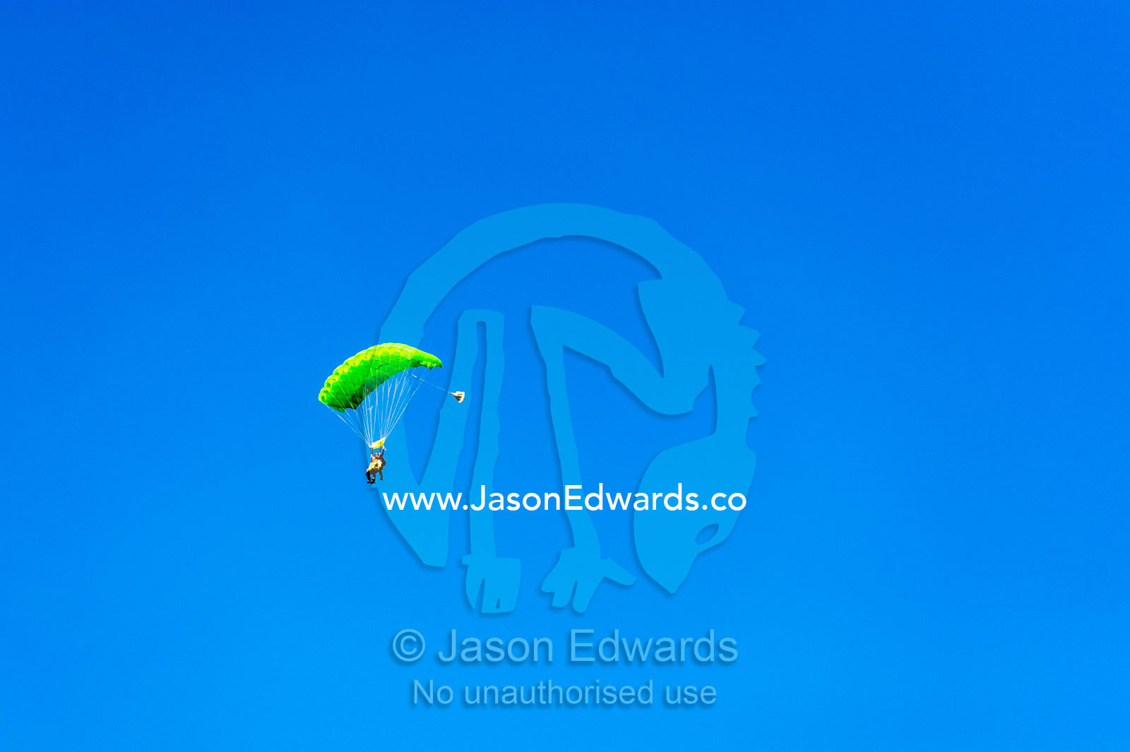 A bright green parachute falls through a clear blue sky. Torquay, Surf Coast, Victoria, Australia.