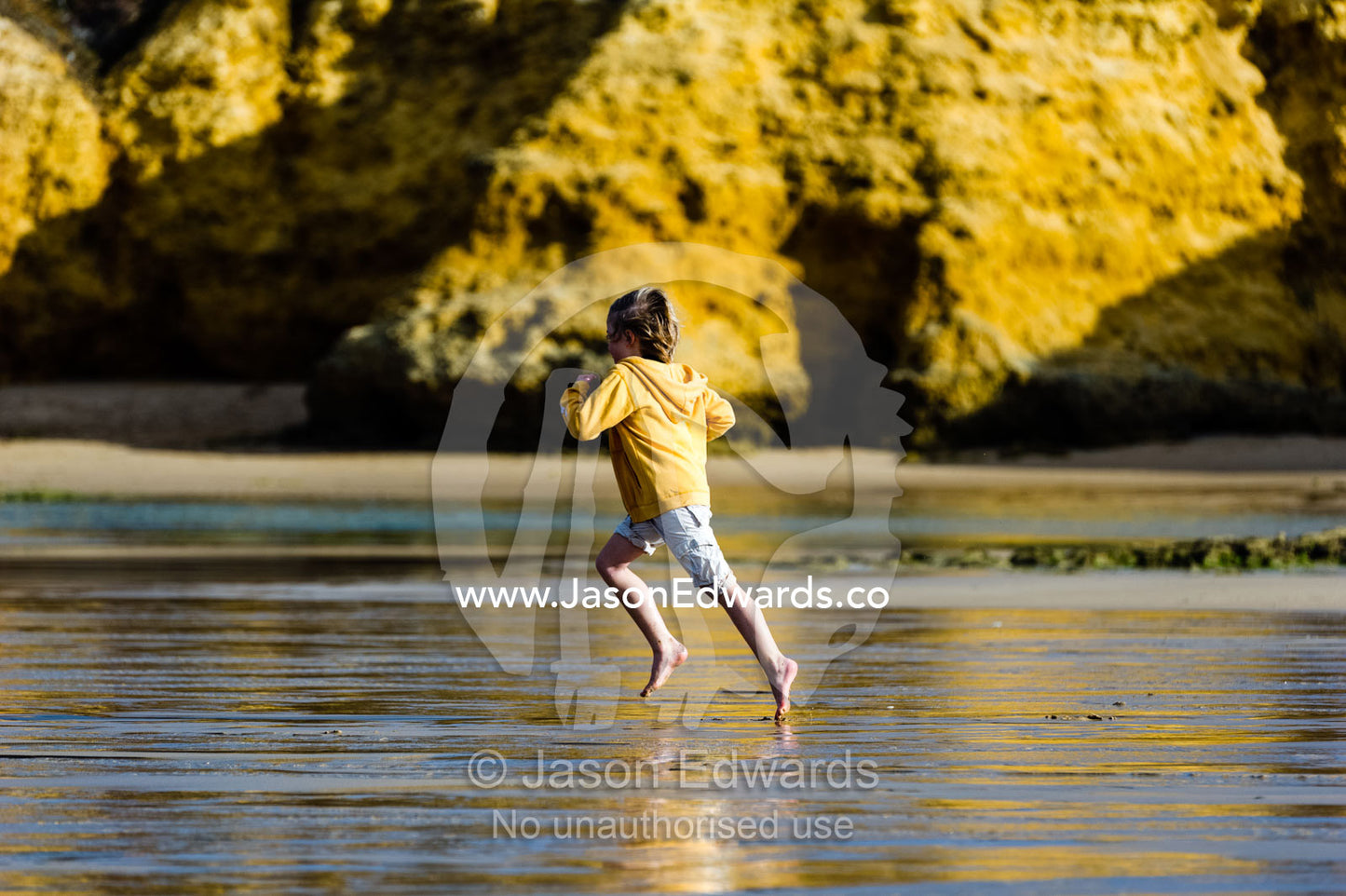 A boy running along the beach at low tide. Torquay, Surf Coast, Victoria, Australia.