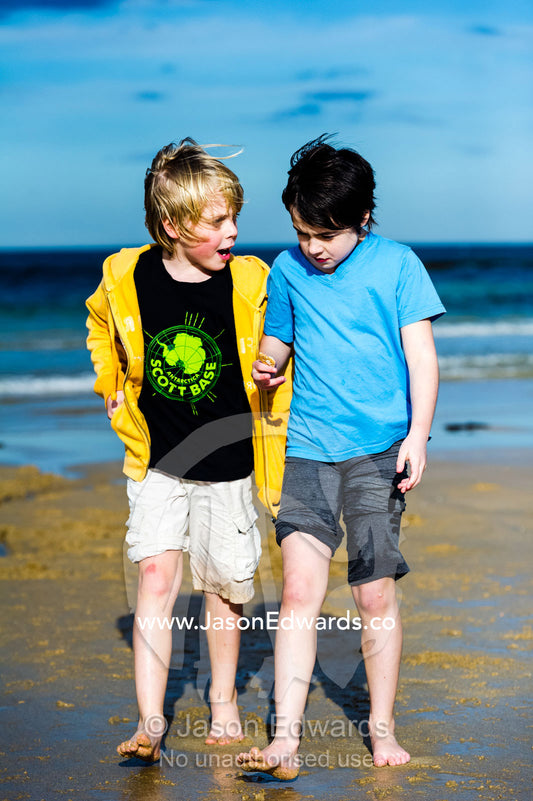 Young friends walking and talking on a beach by the ocean. Torquay, Surf Coast, Victoria, Australia.