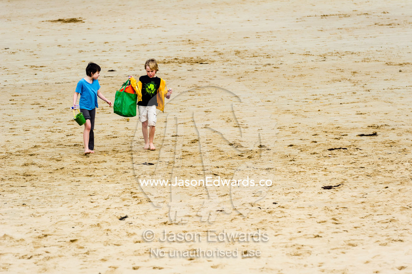 Young friends walking and talking on a beach by the ocean. Torquay, Surf Coast, Victoria, Australia.