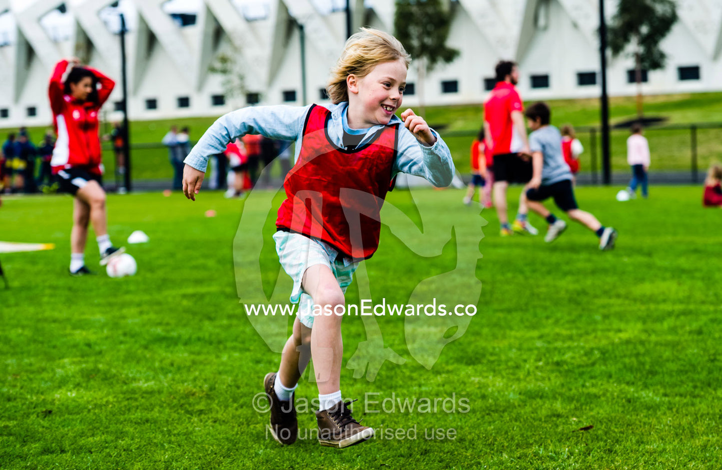 A boy running and playing soccer in a sports field on a school excursion. Albert Park, Melbourne, Victoria, Australia.