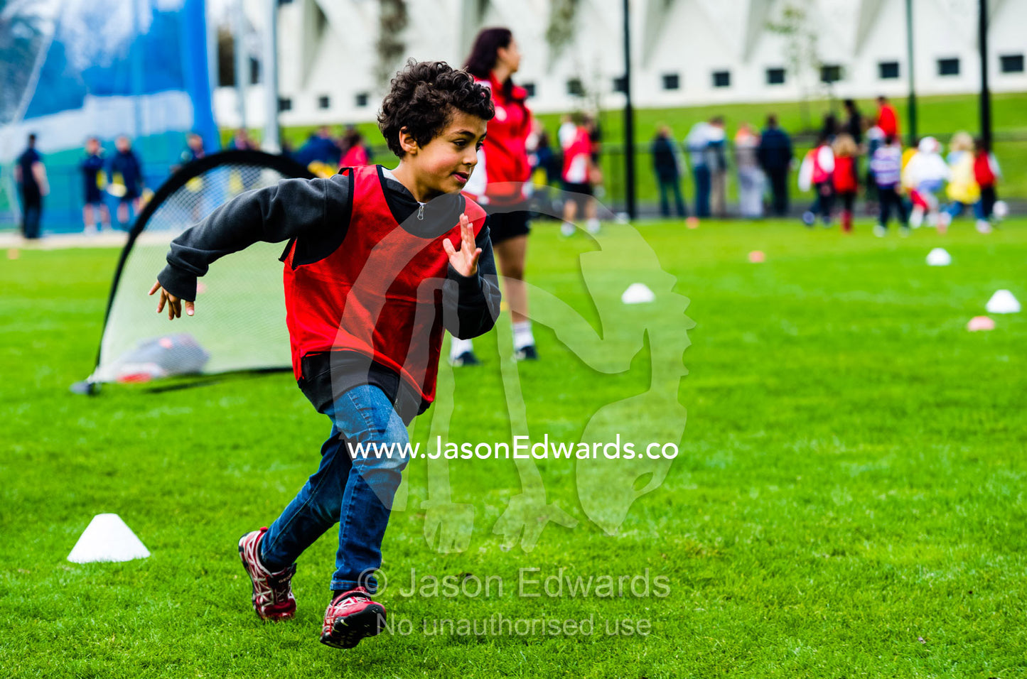 A boy running and playing soccer in a sports field on a school excursion. Albert Park, Melbourne, Victoria, Australia.