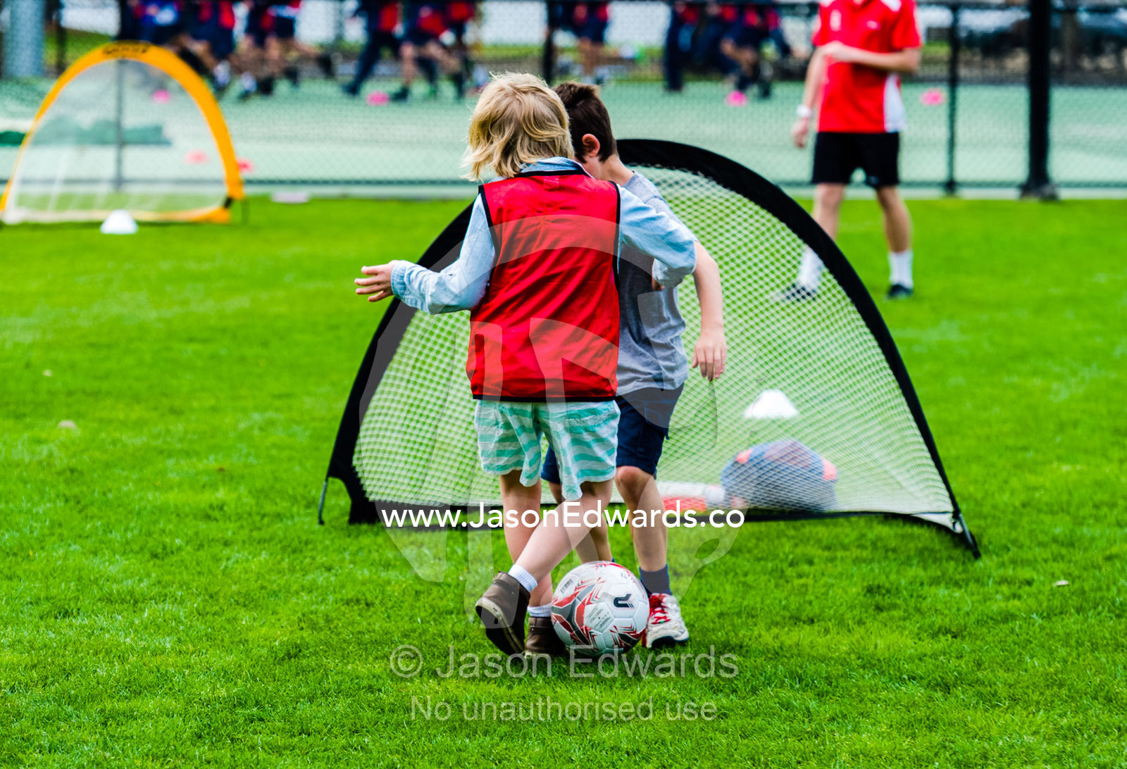 Boys running and playing soccer in a sports field on a school excursion. Albert Park, Melbourne, Victoria, Australia.