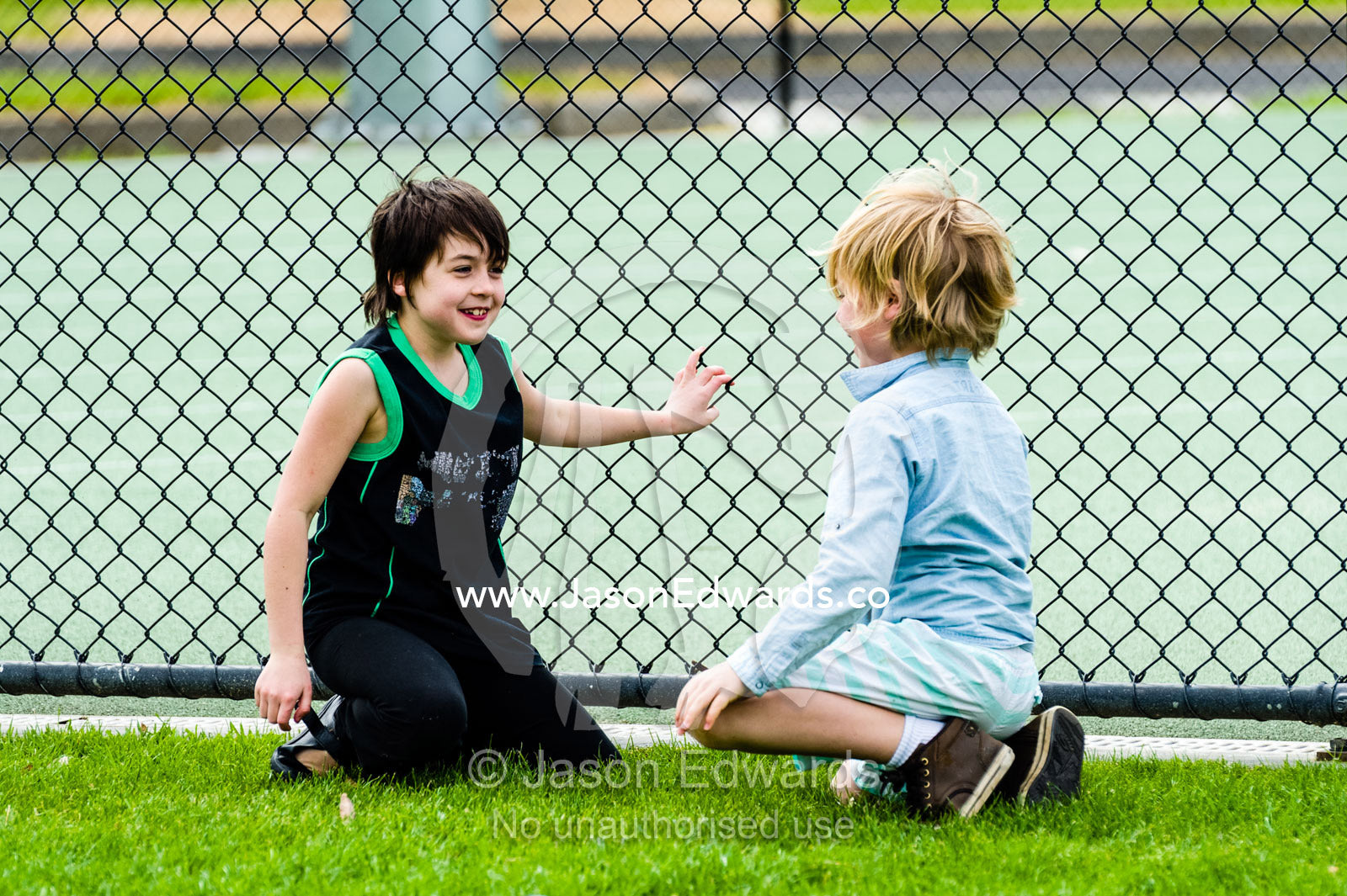 Friends talking on a sports during a school excursion. Albert Park, Melbourne, Victoria, Australia.