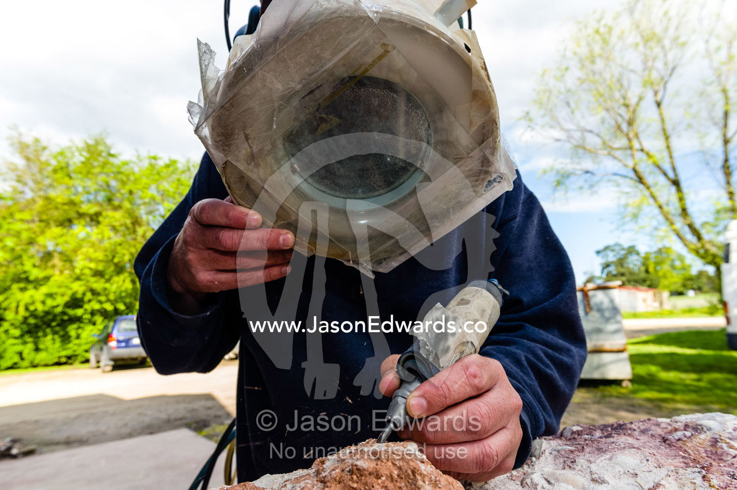 A fossil expert uses a drill and magnifying glass to remove the rock from around the segmented tendrils of a crinoid fossil from the Cretaceous Period that has turned to opal in the desert. Devon Meadows, Melbourne, Victoria, Australia.
