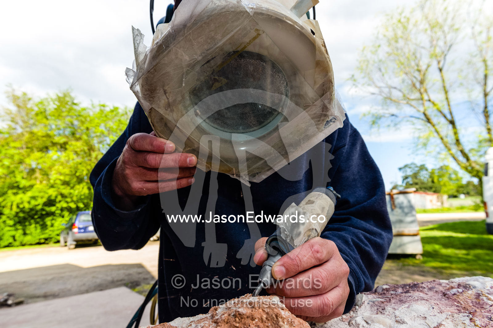 A fossil expert uses a drill and magnifying glass to remove the rock from around the segmented tendrils of a crinoid fossil from the Cretaceous Period that has turned to opal in the desert. Devon Meadows, Melbourne, Victoria, Australia.