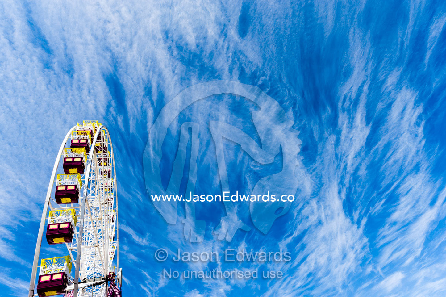 The colorful carriages of a Ferris wheel against a windswept cloudy sky. Royal Melbourne Show, Flemington, Melbourne, Victoria, Australia.