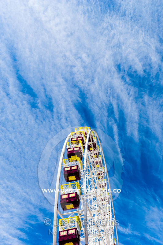 The colorful carriages of a Ferris wheel against a windswept cloudy sky. Royal Melbourne Show, Flemington, Melbourne, Victoria, Australia.