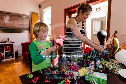 A mother and son packing candy bags for a birthday party. Carlton North, Melbourne, Victoria, Australia.