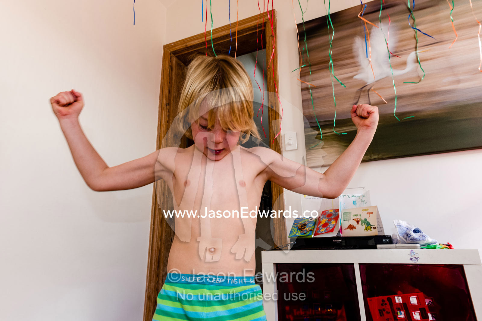 A boy wearing pajamas displays his awesome muscles. Carlton North, Melbourne, Victoria, Australia.