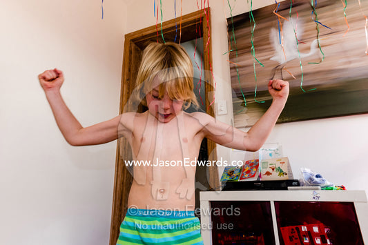 A boy wearing pajamas displays his awesome muscles. Carlton North, Melbourne, Victoria, Australia.