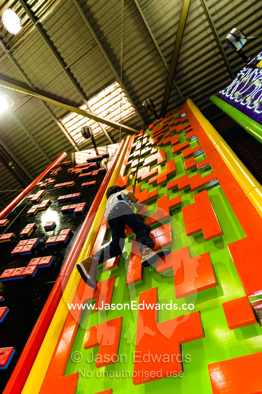 A child scales a colorful wall at a climbing play center. Richmond, Melbourne, Victoria, Australia.