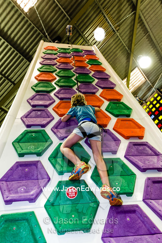 A child scales a colorful wall at a climbing play center. Richmond, Melbourne, Victoria, Australia.